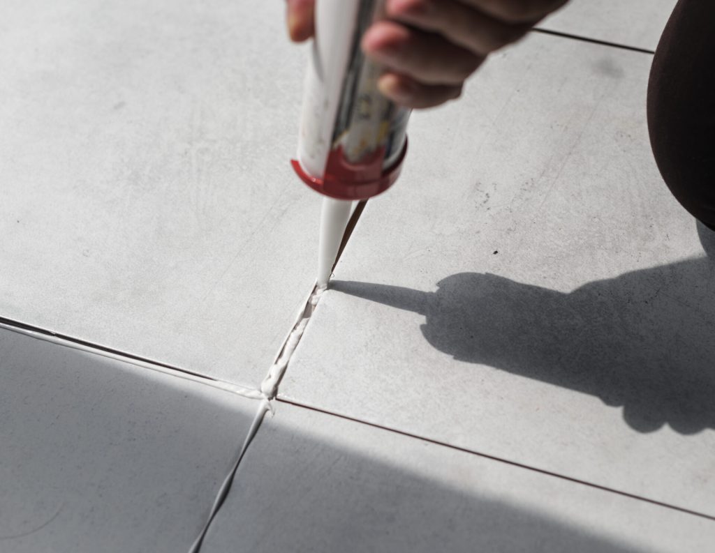Grout being applied between ceramic floor tiles during installation.